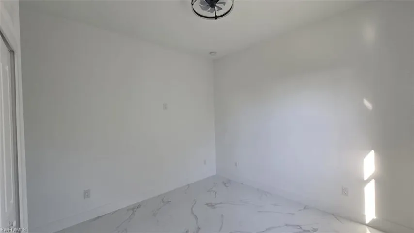 Unfurnished room featuring baseboards and light marble finish flooring