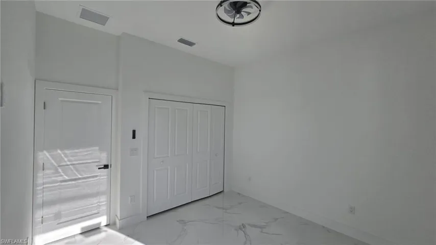 Unfurnished bedroom featuring light marble finish floors and a closet