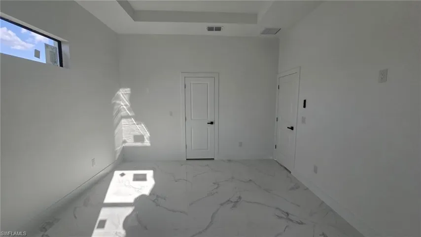 Empty room with light marble finish flooring and a raised ceiling