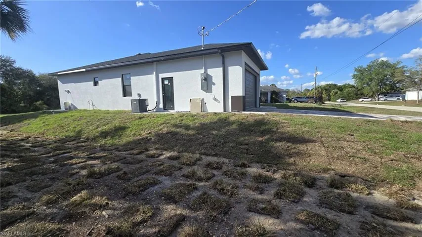 Back of property with stucco siding, a yard, a garage, and driveway