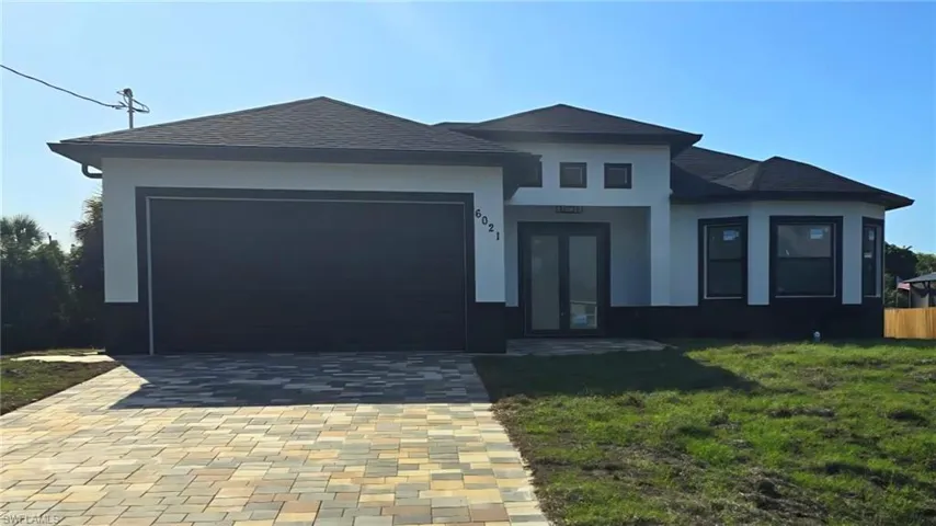 Prairie-style house featuring an attached garage, decorative driveway, a front yard, and stucco siding