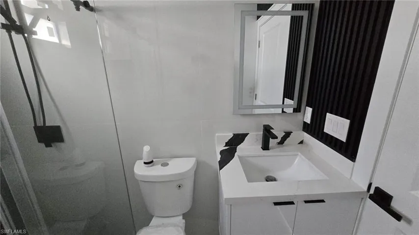 Bathroom featuring vanity, a stall shower, and tile walls