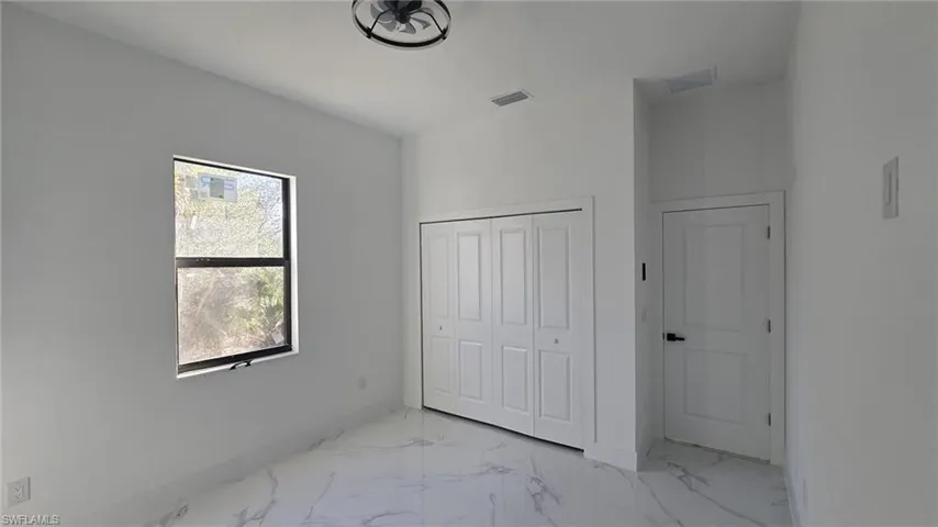 Unfurnished bedroom with light marble finish flooring and a closet