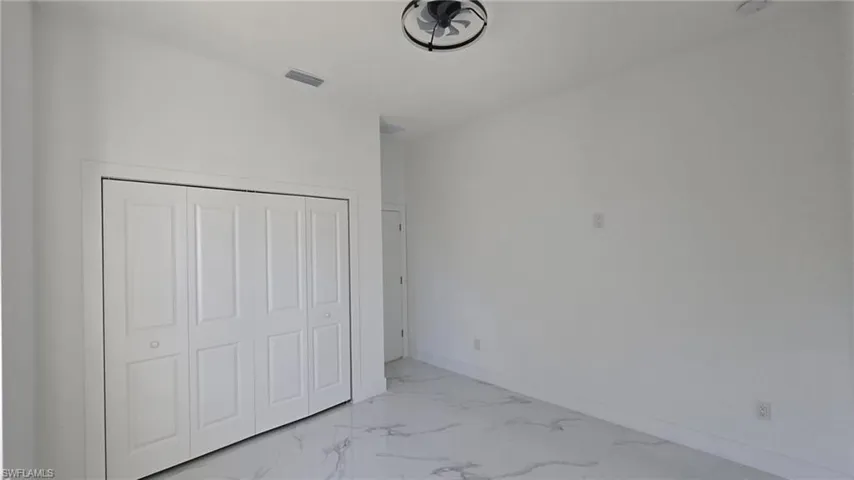 Unfurnished bedroom featuring light marble finish flooring and a closet