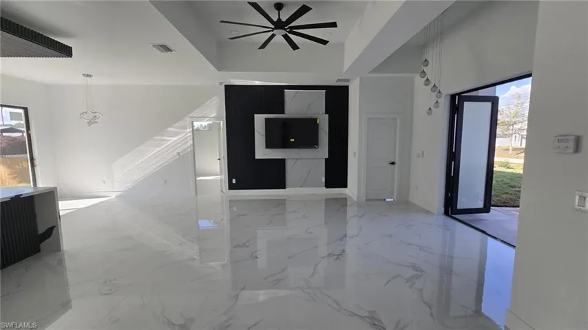 Unfurnished living room with ceiling fan and light marble finish flooring