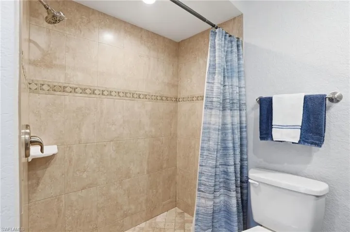 Tiled shower enclosure featuring a decorative accent band and a brushed nickel showerhead