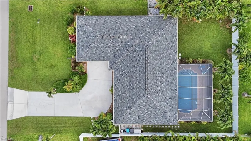 Aerial property overview featuring a shingle roof, expansive green lawn, and a screened swimming pool