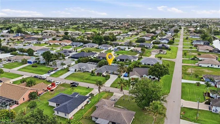 Aerial perspective showcasing a residential neighborhood with single-story homes, green lawns, and mature trees
