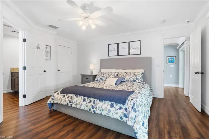 Bedroom featuring wood-finish flooring, white crown molding, and a ceiling fan with integrated lighting