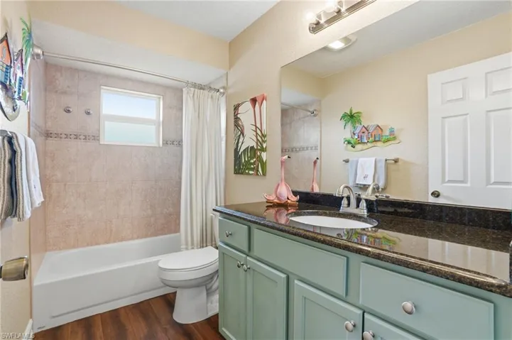 Bathroom featuring a large vanity with a dark stone countertop, an integrated sink with a chrome faucet, and light blue cabinetry