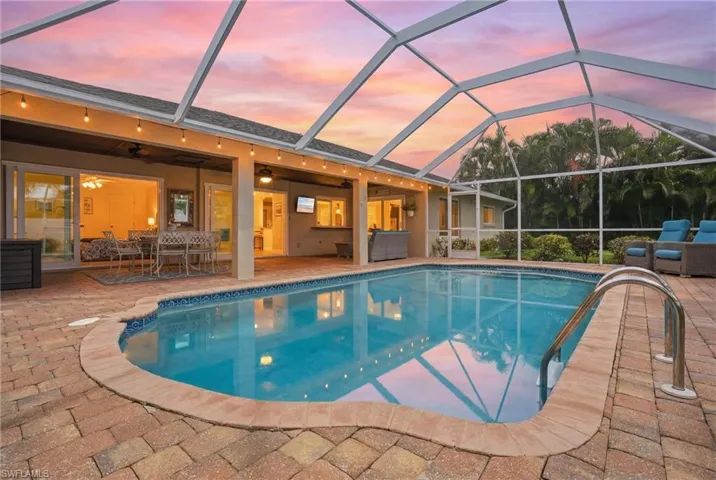 Screened lanai featuring a swimming pool with integrated steps, paver decking, and a covered patio area