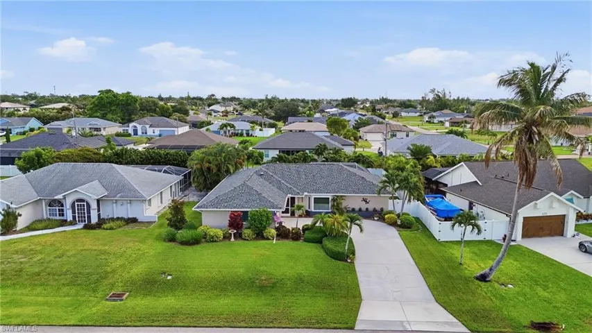 Ranch-style residence featuring a prominent driveway, mature palm trees, and established landscaping