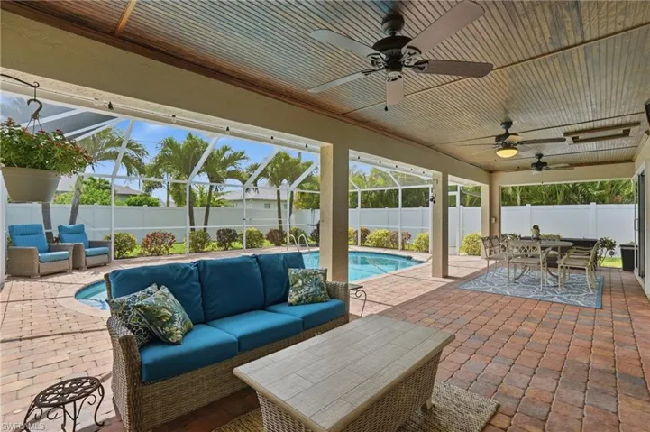 Expansive screened patio featuring a paver deck, a built-in swimming pool, multiple ceiling fans, and a wood-finish ceiling