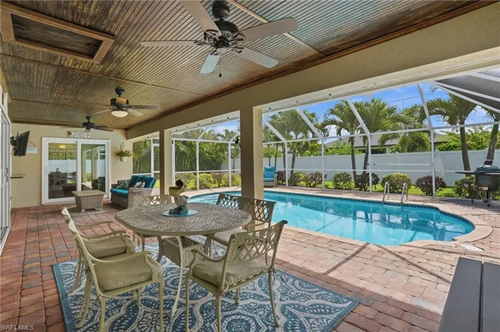 Screened lanai featuring a private swimming pool, paver deck, wood-paneled ceiling, and multiple ceiling fans