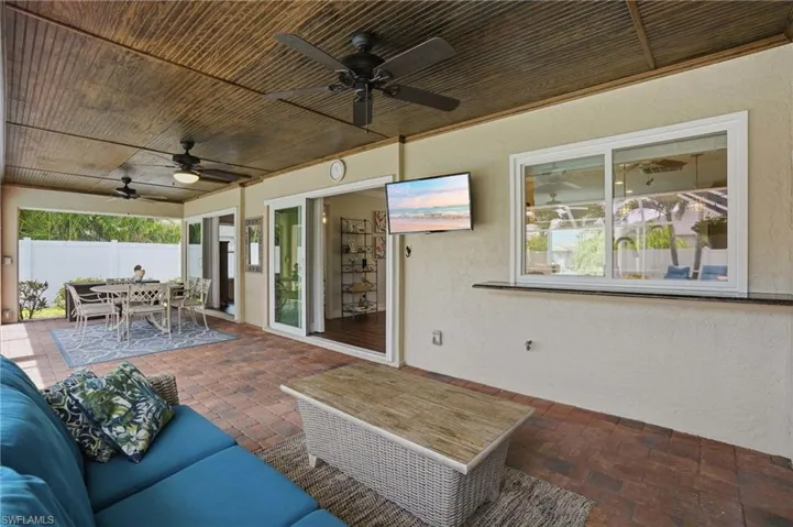 Covered outdoor patio featuring brick paver flooring and a wood-panel ceiling