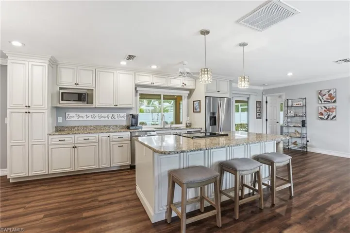 Kitchen featuring white shaker-style cabinetry, stainless steel appliances, granite countertops, and wood-finish flooring