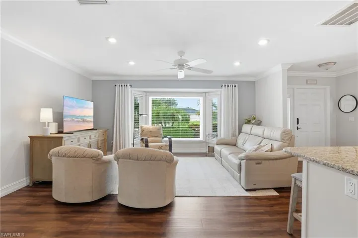 Living area featuring wood-finish flooring, a bay window with blinds, recessed lighting, and a ceiling fan