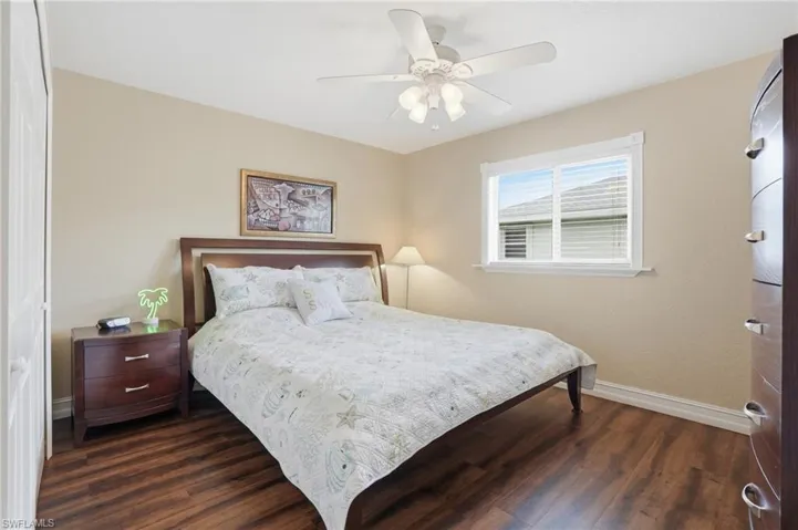 Bedroom featuring wood-finish flooring, a ceiling fan with integrated lighting, and a window with horizontal blinds