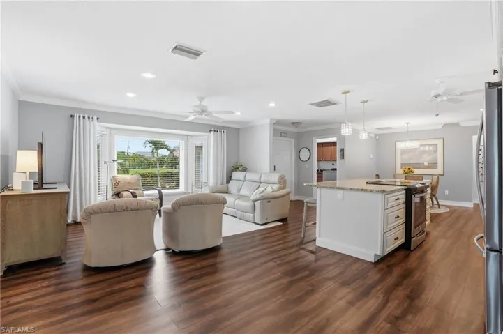 Open-concept living area featuring wood-finish flooring, recessed lighting, and a bay window