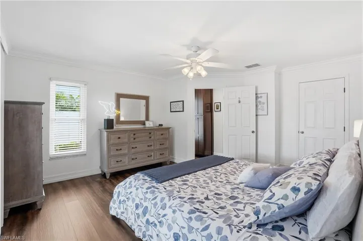 Spacious bedroom featuring wood-finish flooring, white trim, and a ceiling fan