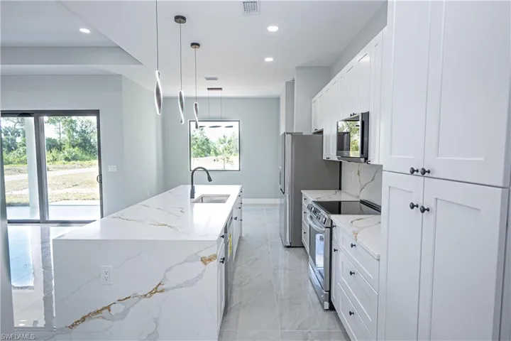 Kitchen with a kitchen island with sink, visible vents, appliances with stainless steel finishes, a sink, and recessed lighting