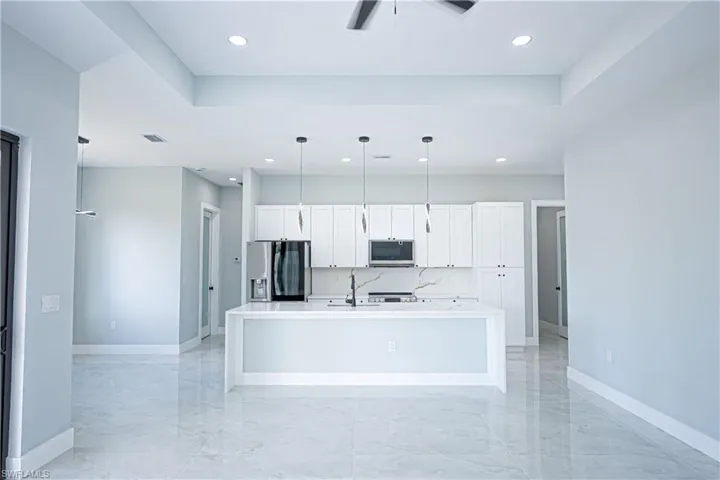 Kitchen with a kitchen island with sink, appliances with stainless steel finishes, baseboards, recessed lighting, and white cabinetry
