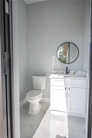 Bathroom featuring baseboards, marble finish floor, toilet, and vanity