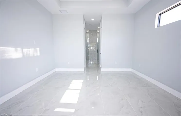 Empty room featuring baseboards, a raised ceiling, and marble finish floor