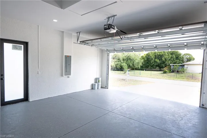 Garage with a garage door opener, a textured wall, and electric panel