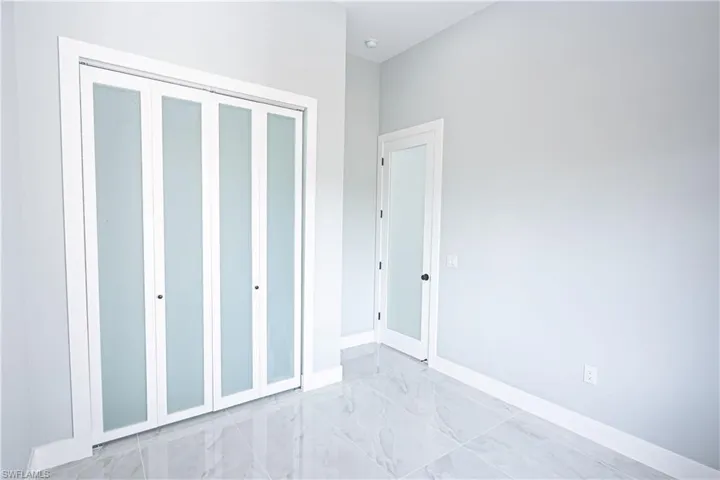 Unfurnished bedroom with a closet, marble finish floor, and baseboards