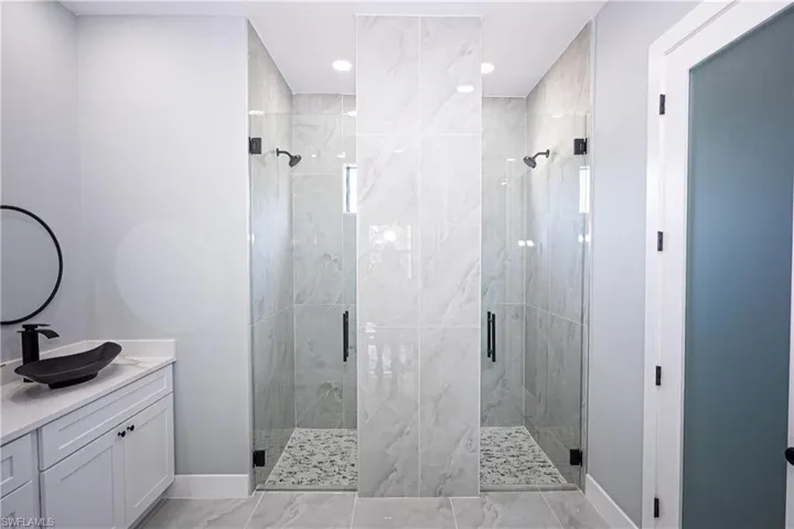 Bathroom with recessed lighting, baseboards, a shower stall, and vanity