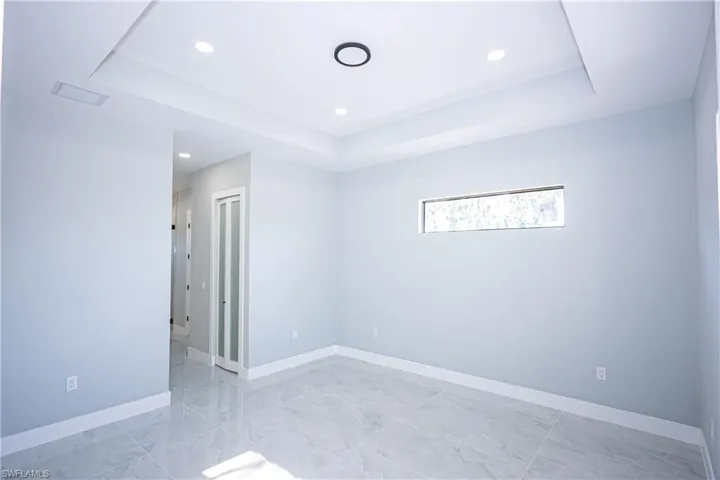 Unfurnished bedroom with a raised ceiling, marble finish floor, recessed lighting, baseboards, and visible vents