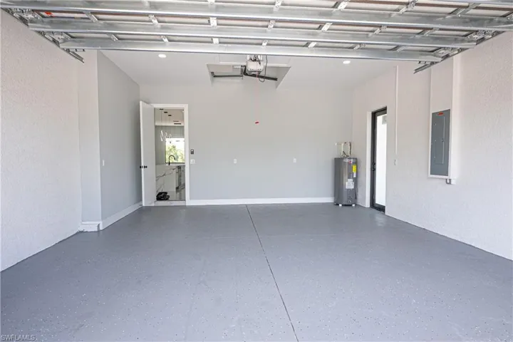 Garage with a garage door opener, water heater, and electric panel