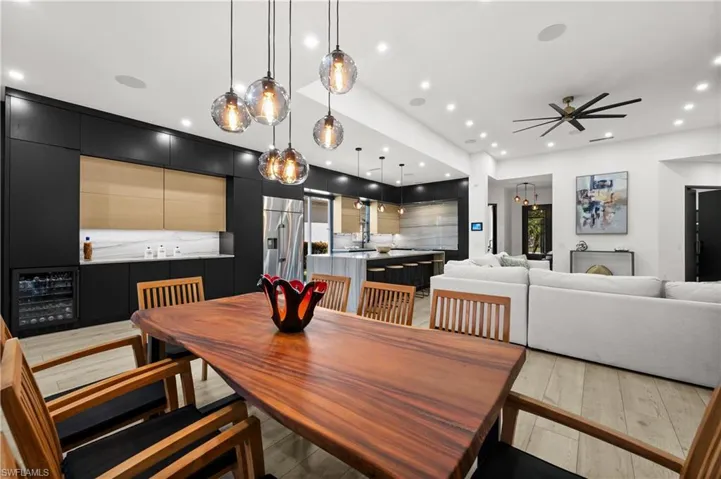 Dining space with ceiling fan, wine cooler, and light hardwood / wood-style flooring