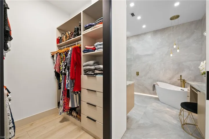 Walk in closet with light hardwood / wood-style floors