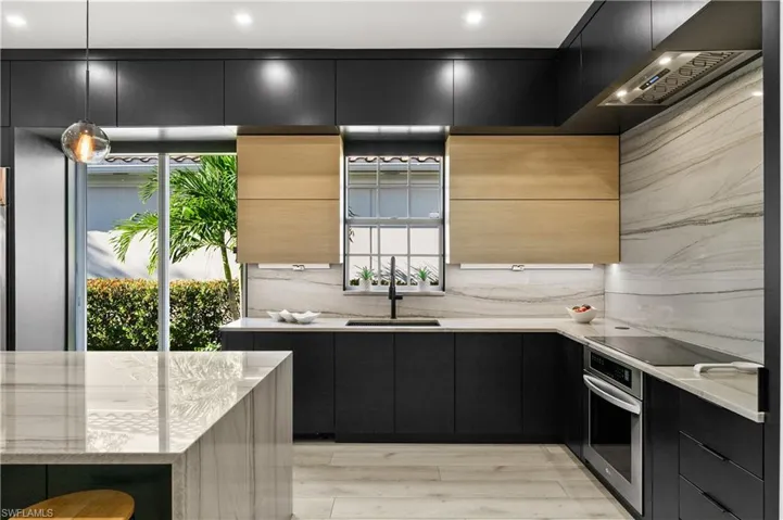 Kitchen with pendant lighting, black electric stovetop, light hardwood / wood-style floors, sink, and stainless steel oven