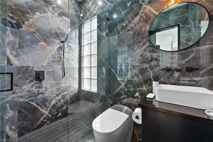 Bathroom with vanity, tile walls, toilet, and a shower with door