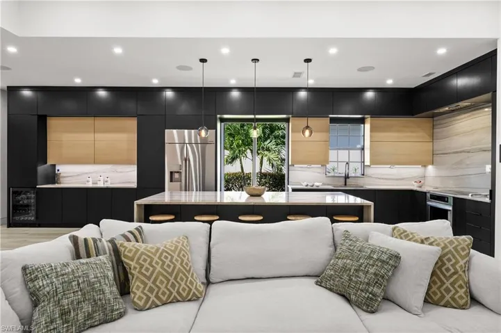 Kitchen with pendant lighting, a center island, sink, stainless steel appliances, and backsplash