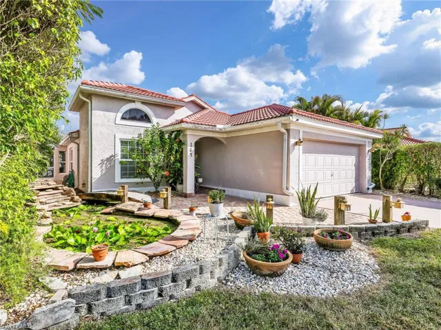 Mediterranean / spanish-style home featuring stucco siding, an attached garage, driveway, and a tiled roof