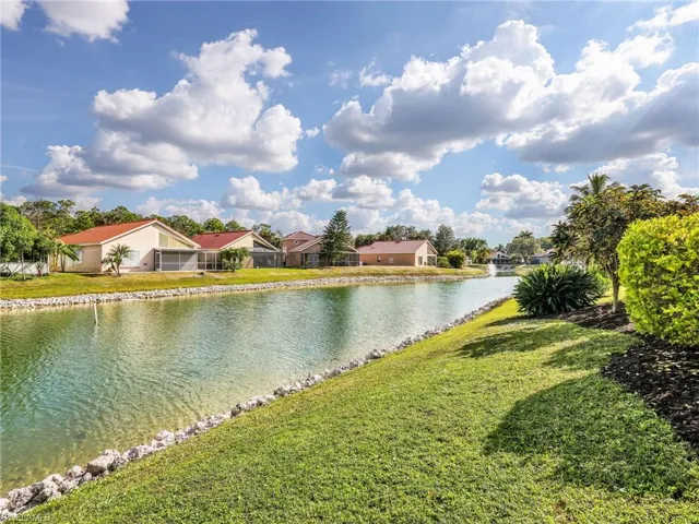 Expansive canal-front setting with a manicured lawn, established landscaping, and a rock-lined shoreline