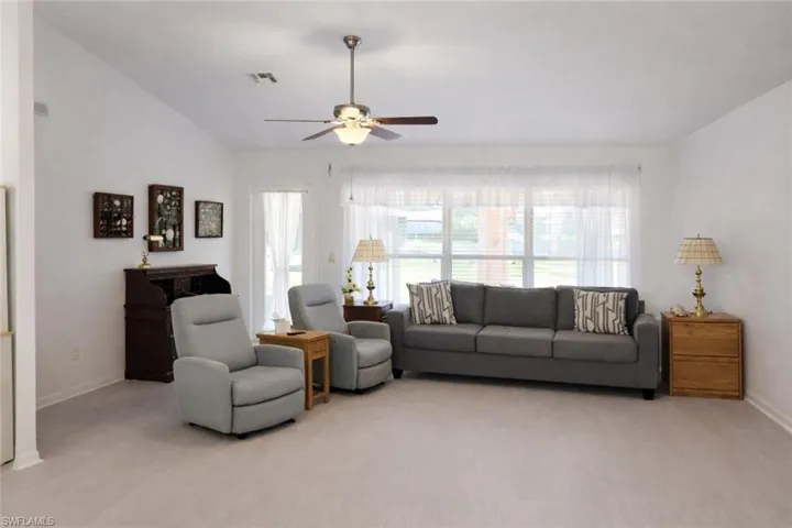 Living room featuring ceiling fan, light colored carpet, and vaulted ceiling