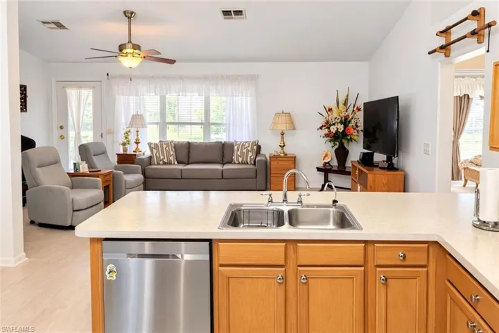 Kitchen with light countertops, open floor plan, stainless steel dishwasher, and a ceiling fan