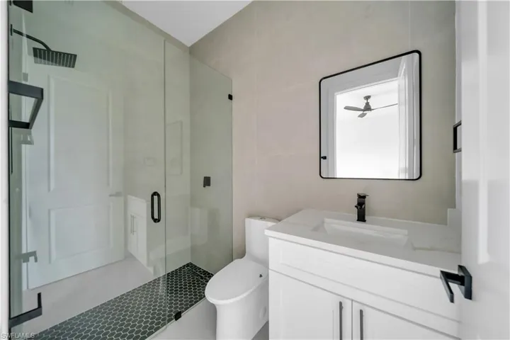Bathroom featuring a stall shower, vanity, and tile walls
