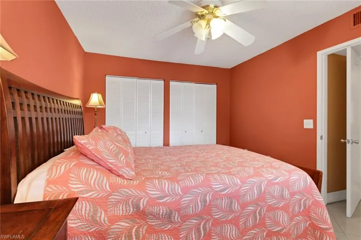 Tiled bedroom with multiple closets, a ceiling fan, and a textured ceiling