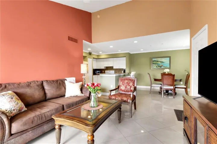 Living room with a towering ceiling, light tile patterned flooring, and recessed lighting