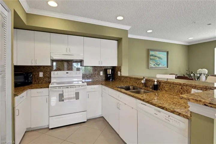 Kitchen featuring ornamental molding, white appliances, a textured ceiling, white cabinets, and light tile patterned floors