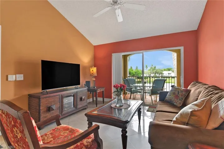 Living area featuring light tile patterned flooring, vaulted ceiling, a ceiling fan, and a textured ceiling