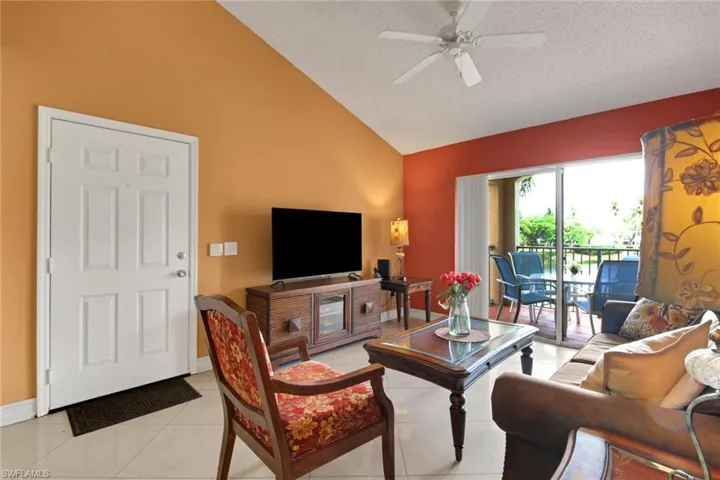 Living area featuring light tile patterned floors, ceiling fan, a textured ceiling, and high vaulted ceiling