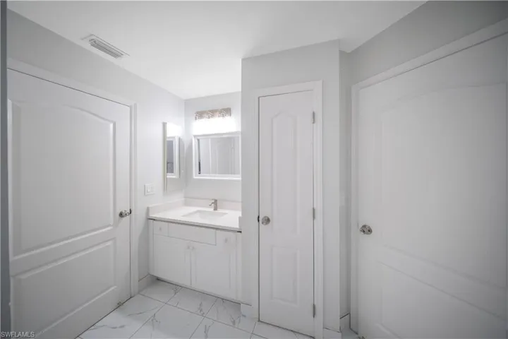 Bathroom featuring vanity and light marble finish floors