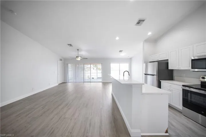 Kitchen featuring stainless steel appliances, white cabinetry, a kitchen island with sink, recessed lighting, and light wood-style floors